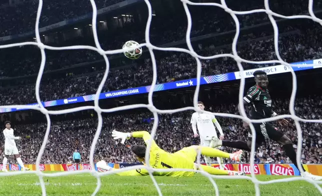 Arsenal's Bukayo Saka, right, scores the opening goal during the Champions League quarterfinals second leg soccer match between Real Madrid and Arsenal at the Santiago Bernabeu stadium in Madrid, Wednesday, April 16, 2025. (AP Photo/Manu Fernandez)