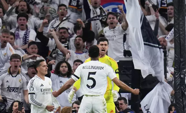 Real Madrid's goalkeeper Thibaut Courtois, right, reacts after saving a penalty shot by Arsenal's Bukayo Saka during the Champions League quarterfinals second leg soccer match between Real Madrid and Arsenal at the Santiago Bernabeu stadium in Madrid, Wednesday, April 16, 2025. (AP Photo/Manu Fernandez)