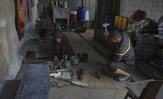 Displaced Palestinians Karima and Ibrahim Al-Kafarna prepare a fire to cook for their children at their makeshift home inside the destroyed Rashad Al Shawa Cultural Center in Gaza City, Monday, April 21, 2025. (AP Photo/Jehad Alshrafi)