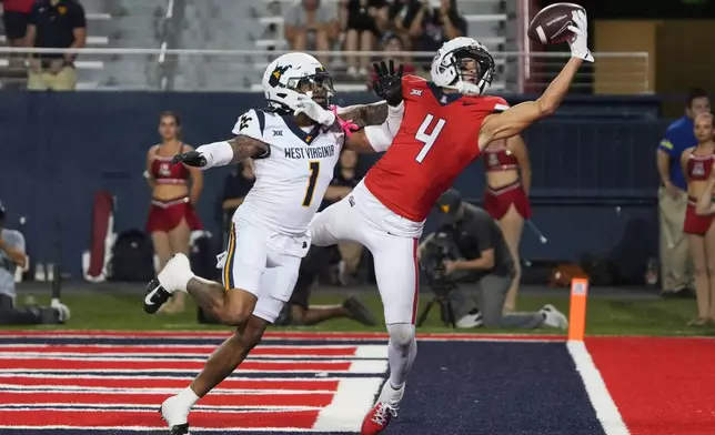 FILE - Arizona wide receiver Tetairoa McMillan (4) reaches for the ball over West Virginia cornerback Garnett Hollis Jr. in the second half during an NCAA college football game, Saturday, Oct. 26, 2024, in Tucson, Ariz. (AP Photo/Rick Scuteri, File)