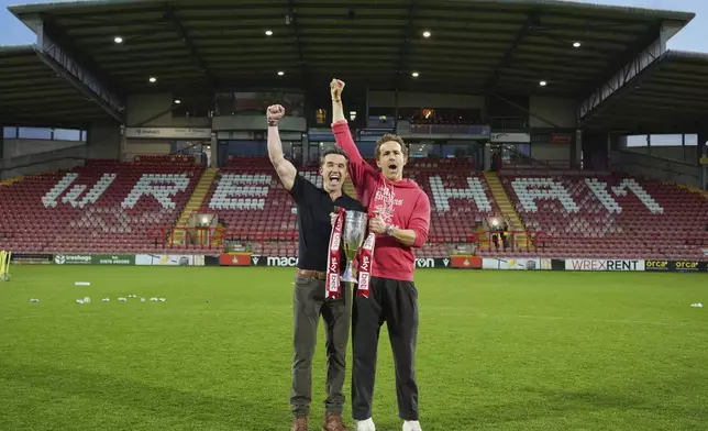 Wrexham co-owners Rob McElhenney, left, and Ryan Reynolds pose with trophy at the end of the English League One soccer match between Wrexham and Charlton Athletic at the Racecourse ground in Wrexham, Wales, Saturday, April 26, 2025. (AP Photo/Jon Super)