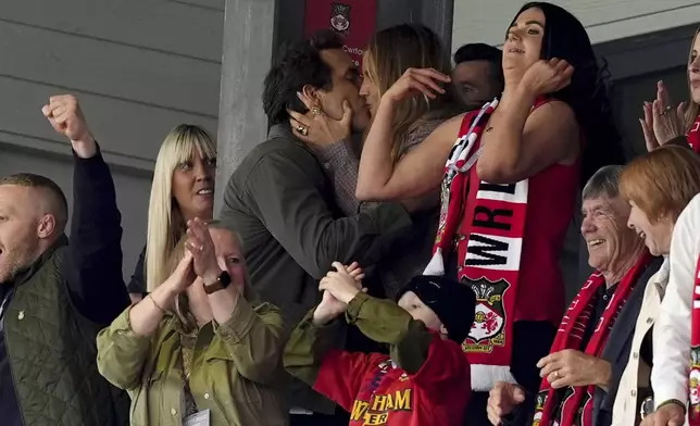 Wrexham co-owner Ryan Reynolds, top left, kisses his wife Blake Lively after Wrexham scored their first goal English League One soccer match between Wrexham and Charlton Athletic at the Racecourse ground in Wrexham, Wales, Saturday, April 26, 2025. (Martin Rickett/PA via AP)