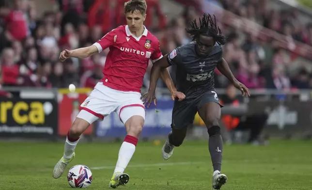 Wrexham's Max Cleworth, left, duels for the ball with Charlton Athletic's Tyreece Campbell during the English League One soccer match between Wrexham and Charlton Athletic at the Racecourse ground in Wrexham, Wales, Saturday, April 26, 2025. (AP Photo/Jon Super)