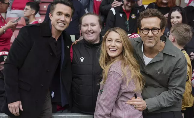 Wrexham co-owners Ryan Reynolds, right, his wife Blake Lively, second right, and Rob McElhenney, left, pose with fans before the English League One soccer match between Wrexham and Charlton Athletic at the Racecourse ground in Wrexham, Wales, Saturday, April 26, 2025. (AP Photo/Jon Super)