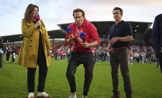 Wrexham co-owners Ryan Reynolds, center, and Rob McElhenney celebrate at the end of the English League One soccer match between Wrexham and Charlton Athletic at the Racecourse ground in Wrexham, Wales, Saturday, April 26, 2025. (AP Photo/Jon Super)