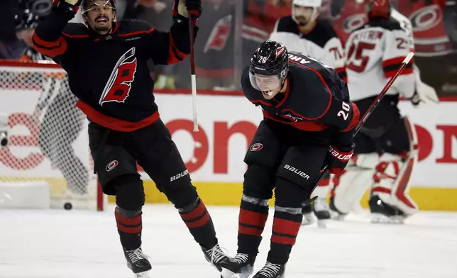 Carolina Hurricanes' Sebastian Aho (20) celebrate his game-winning goal with Seth Jarvis (24) during the second overtime period of Game 5 of an NHL hockey first-round playoff series against the New Jersey Devils in Raleigh, N.C., Tuesday, April 29, 2025. (AP Photo/Karl DeBlaker)