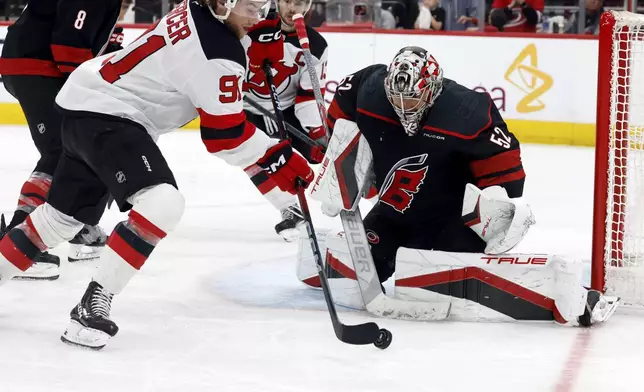 New Jersey Devils' Dawson Mercer (91) tries to settle the puck in front of Carolina Hurricanes goaltender Pyotr Kochetkov (52) during the third period of Game 5 of an NHL hockey Stanley Cup first-round playoff series in Raleigh, N.C., Tuesday, April 29, 2025. (AP Photo/Karl DeBlaker)