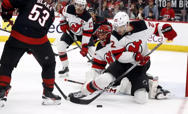 New Jersey Devils' Brett Pesce (22) clears the puck away from Carolina Hurricanes' Jackson Blake (53) during the second period of Game 5 of an NHL hockey Stanley Cup first-round playoff series in Raleigh, N.C., Tuesday, April 29, 2025. (AP Photo/Karl DeBlaker)