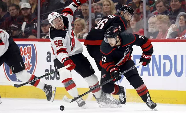 Carolina Hurricanes' Logan Stankoven (22) gathers in the puck around teammate Sean Walker (26) and in front of New Jersey Devils' Erik Haula (56) during the third period of Game 5 of an NHL hockey Stanley Cup first-round playoff series in Raleigh, N.C., Tuesday, April 29, 2025. (AP Photo/Karl DeBlaker)