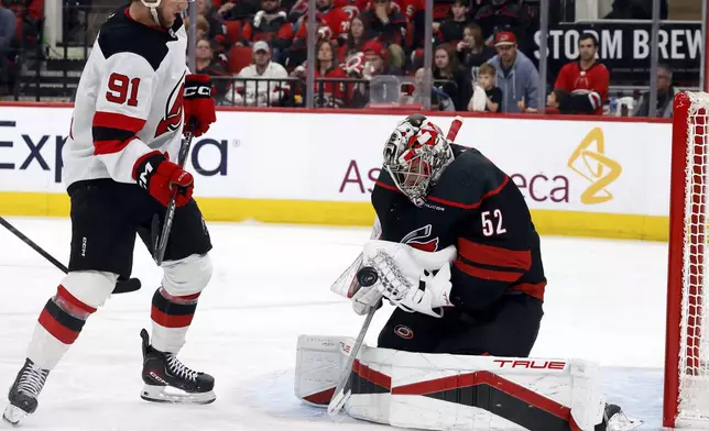 Carolina Hurricanes goaltender Pyotr Kochetkov (52) controls the puck in front of New Jersey Devils' Dawson Mercer (91) during the third period of Game 5 of an NHL hockey Stanley Cup first-round playoff series in Raleigh, N.C., Tuesday, April 29, 2025. (AP Photo/Karl DeBlaker)