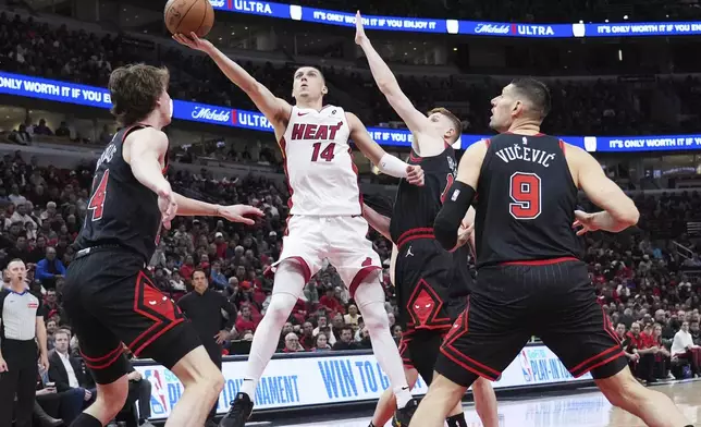 Miami Heat guard Tyler Herro (14) drives to the basket against Chicago Bulls forward Matas Buzelis, left, guard Kevin Huerter and center Nikola Vucevic, right, during the first half of an NBA play-in tournament basketball game in Chicago, Wednesday, April 16, 2025. (AP Photo/Nam Y. Huh)