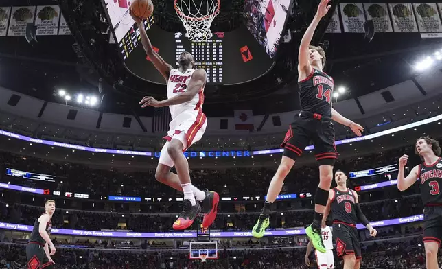 Miami Heat forward Andrew Wiggins, left, drives to the basket past Chicago Bulls forward Matas Buzelis during the first half of an NBA play-in tournament basketball game in Chicago, Wednesday, April 16, 2025. (AP Photo/Nam Y. Huh)