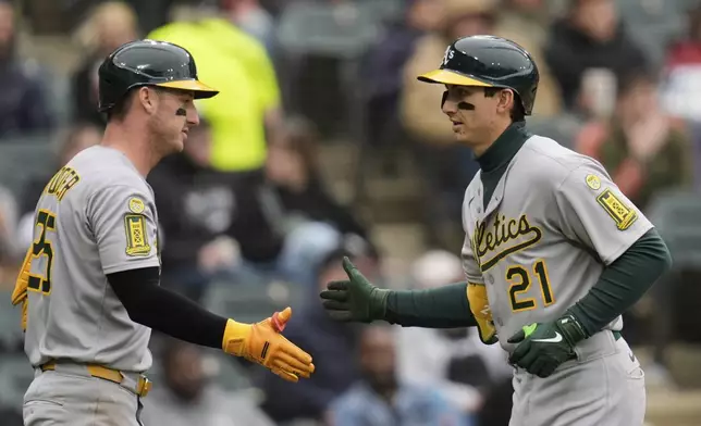 Athletics' Tyler Soderstrom (21) slaps hands with Brent Rooker, left, after hitting a home run during the seventh inning of a baseball game against the Chicago White Sox, Thursday, April 17, 2025, in Chicago. (AP Photo/Erin Hooley)