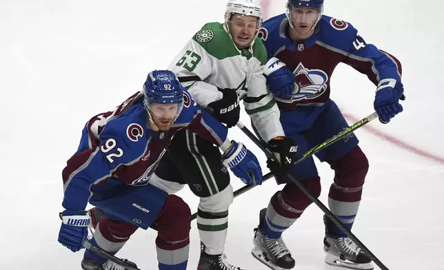 Dallas Stars right wing Evgenii Dadonov, center, is sandwiched between Colorado Avalanche left wing Gabriel Landeskog, left, and defenseman Josh Manson in the third period of Game 4 of an NHL hockey first-round playoff series Saturday, April 26, 2025, in Denver. (AP Photo/David Zalubowski)