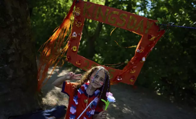 A girl poses for a picture as people celebrated King's Day in Amsterdam, Netherlands, Saturday, April 26, 2025. (AP Photo/Peter Dejong)