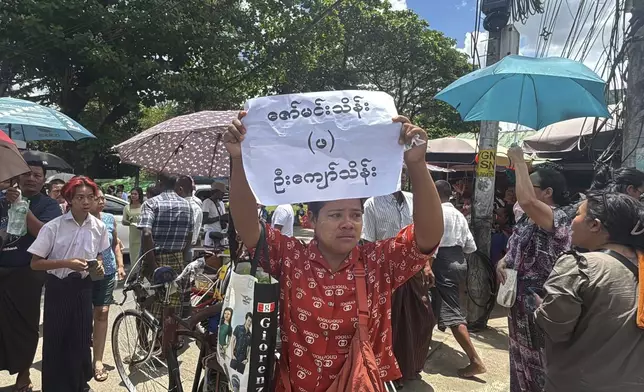 A person holds a sign of name as family members and colleagues wait to welcome released prisoners outside the main gate of Insein prison Thursday, April 17, 2025, in Yangon, Myanmar. (AP Photo/Thein Zaw)