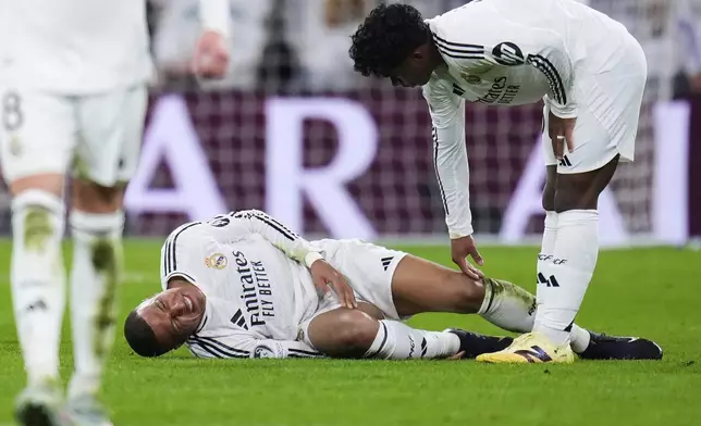 Real Madrid's Kylian Mbappe grimaces on the ground after getting injured during the Champions League quarterfinals second leg soccer match between Real Madrid and Arsenal at the Santiago Bernabeu stadium in Madrid, Wednesday, April 16, 2025. (AP Photo/Manu Fernandez)