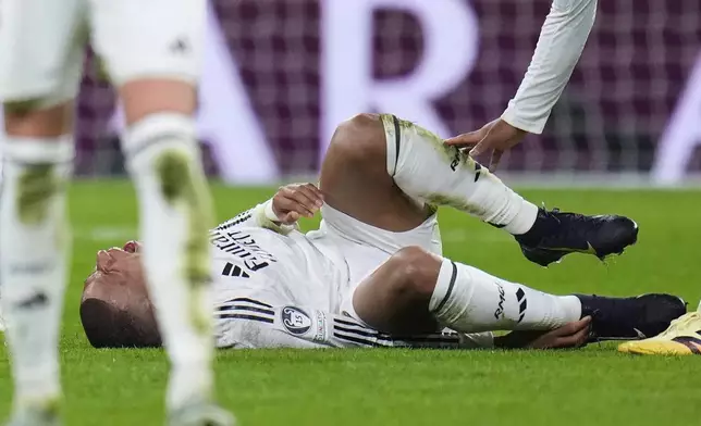 Real Madrid's Kylian Mbappe grimaces on the ground after getting injured during the Champions League quarterfinals second leg soccer match between Real Madrid and Arsenal at the Santiago Bernabeu stadium in Madrid, Wednesday, April 16, 2025. (AP Photo/Manu Fernandez)