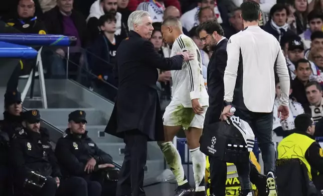 Real Madrid's Kylian Mbappe walks past Real Madrid's head coach Carlo Ancelotti after being replaced during the Champions League quarterfinals second leg soccer match between Real Madrid and Arsenal at the Santiago Bernabeu stadium in Madrid, Wednesday, April 16, 2025. (AP Photo/Manu Fernandez)