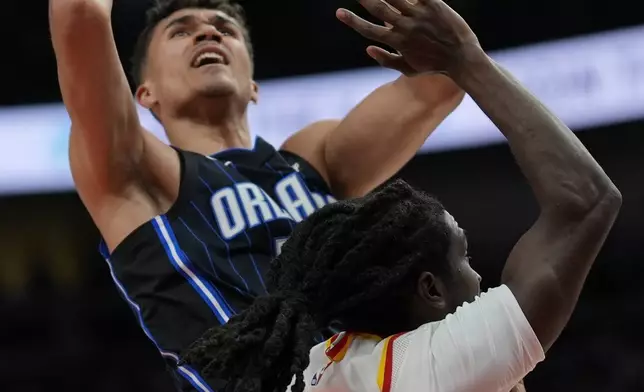 Orlando Magic guard Caleb Houstan (2) shoots against Atlanta Hawks guard Keaton Wallace (2) during the first half of an NBA basketball game, Sunday, April 13, 2025, in Atlanta. (AP Photo/Mike Stewart)