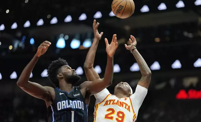 Atlanta Hawks guard Daeqwon Plowden (29) and Orlando Magic forward Jonathan Isaac (1) chase a rebound during the first half of an NBA basketball game, Sunday, April 13, 2025, in Atlanta. (AP Photo/Mike Stewart)