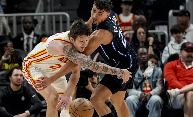 Atlanta Hawks guard Vit Krejci (27) and Orlando Magic forward Tristan da Silva (23) chase a loose ball during the first half of an NBA basketball game, Sunday, April 13, 2025, in Atlanta. (AP Photo/Mike Stewart)