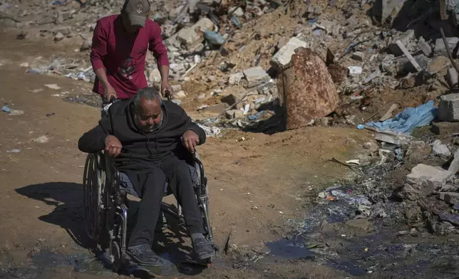 Wasem Attiya pushes his father, Mohamed, 54, in a wheelchair as they head to Shifa hospital in Gaza City for a dialysis session, Monday, April 14, 2025. (AP Photo/Jehad Alshrafi)