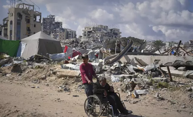 Wasem Attiya pushes his father, Mohamed, 54, in a wheelchair as they head to Shifa hospital in Gaza City for a dialysis session, Monday, April 14, 2025. (AP Photo/Jehad Alshrafi)