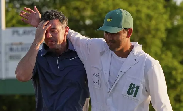 Rory McIlroy, of Northern Ireland, left, is embraced by caddie Harry Diamond after winning in a playoff against Justin Rose, of England, after the final round the Masters golf tournament, Sunday, April 13, 2025, in Augusta, Ga. (AP Photo/David J. Phillip)