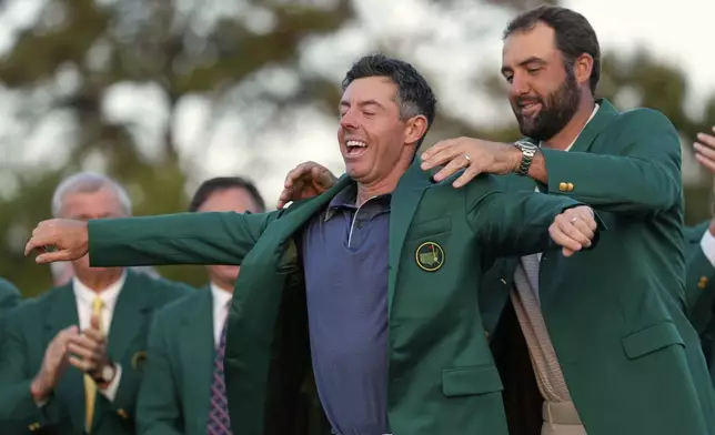 Scottie Scheffler puts the green Jacket on winner, Rory McIlroy, of Northern Ireland, at the Masters golf tournament, Sunday, April 13, 2025, in Augusta, Ga. (AP Photo/Ashley Landis)