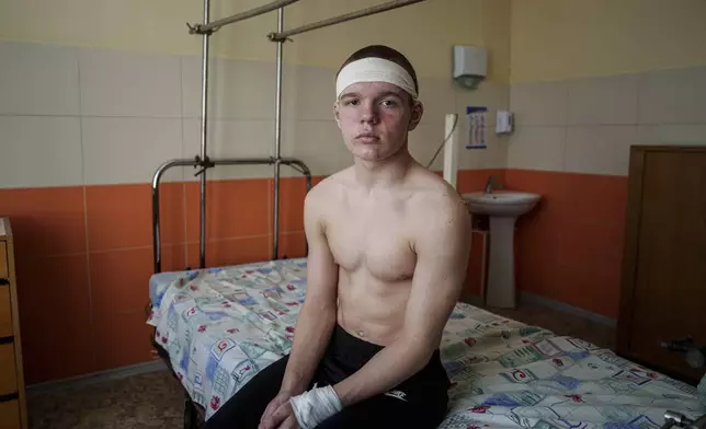 Kyrylo Illiashenko, 13, sits on a hospital bed, Monday, April 14, 2025, after being injured on Sunday by a Russian missile strike on Sumy, Ukraine, while trying to help others evacuate a burning bus that he later exited through a shattered window. (AP Photo/Evgeniy Maloletka)
