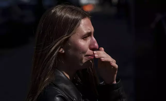 Kateryna Sitak, 23, a teacher, cries after laying flowers and toys on a site of a Russian missile strike in Sumy, Ukraine, Monday, April 14, 2025. (AP Photo/Evgeniy Maloletka)