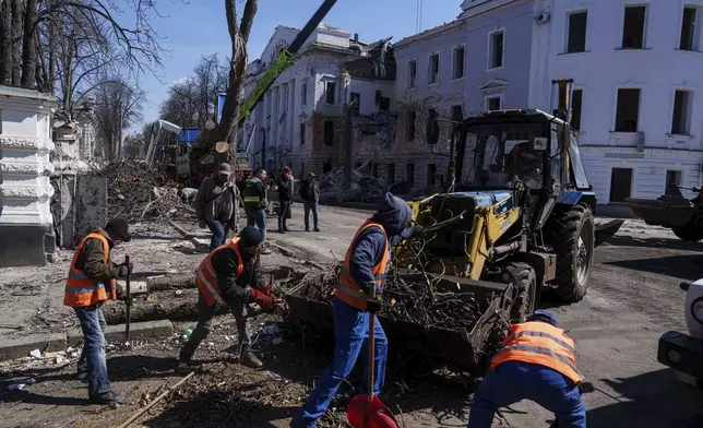 Municipal workers clean a street in front of a University building destroyed by a Russian missile strike in Sumy, Ukraine, Monday, April 14, 2025. (AP Photo/Evgeniy Maloletka)