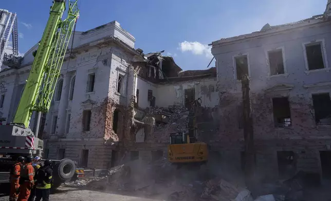 An excavator clears the rubble from a University building destroyed by a Russian missile strike in Sumy, Ukraine, Monday, April 14, 2025. (AP Photo/Evgeniy Maloletka)