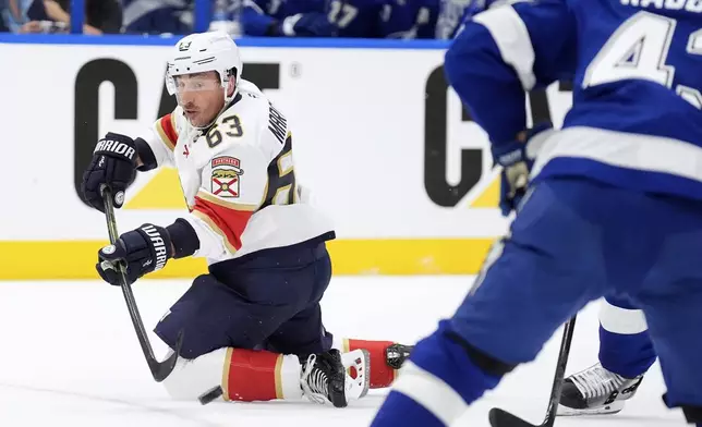 Florida Panthers center Brad Marchand (63) passes the puck after getting knocked down during the first period in Game 1 of an NHL hockey Stanley Cup first-round playoff series, against the Tampa Bay Lightning Tuesday, April 22, 2025, in Tampa, Fla. (AP Photo/Chris O'Meara)