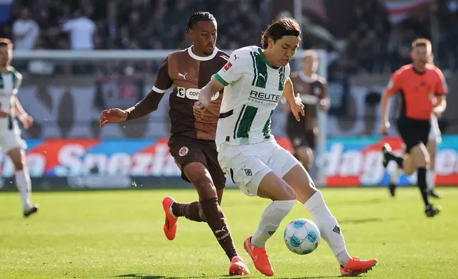 St. Pauli's Morgan Guilavogui and M'nchengladbach's Ko Itakura, right, fight for the ball during the German Bundesliga soccer game between FC St. Pauli and Borussia M'nchengladbach at Millerntor-Stadion in Hamburg, Germany, Sunday, April 6, 2025. (Christian Charisius/dpa via AP)
