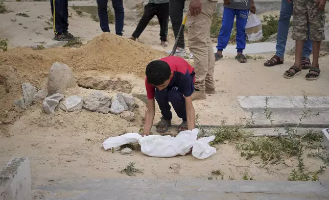 A boy carries the body of 15-day-old premature infant Sila Zidane, who died from sepsis a few days after her twin sister, following their premature birth to mother Yasmine Zakout, to be buried at the cemetery in Deir al-Balah, central Gaza Strip, Wednesday, April 23, 2025. (AP Photo/Abdel Kareem Hana)