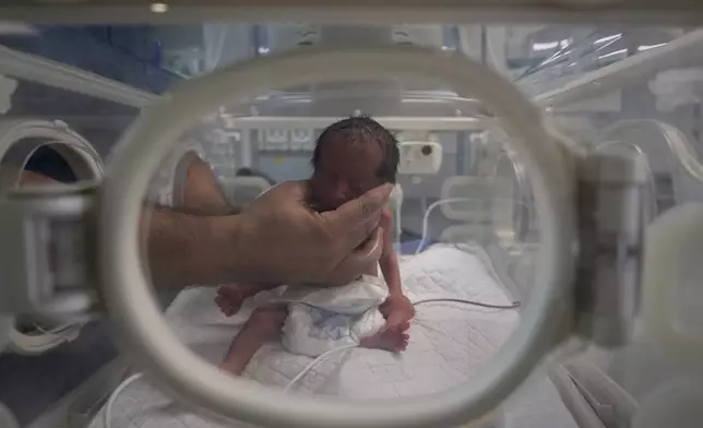 A nurse holds a prematurely born baby suffering from respiratory problems inside an incubator at Nasser Hospital in Khan Younis, southern Gaza Strip, Wednesday, April 23, 2025. (AP Photo/Abdel Kareem Hana)