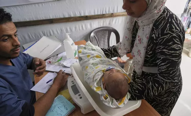 Doctors weigh a Palestinian baby at the Médecins Sans Frontières (MSF) clinic in Muwasi, near Khan Younis in the southern Gaza Strip, Tuesday, April 8, 2025. (AP Photo/Abdel Kareem Hana)