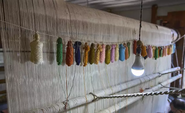 Colorful silk weaving threads are hung from above a loom at a carpet factory in Srinagar, Indian controlled Kashmir, on April 14, 2025. (AP Photo/Dar Yasin)