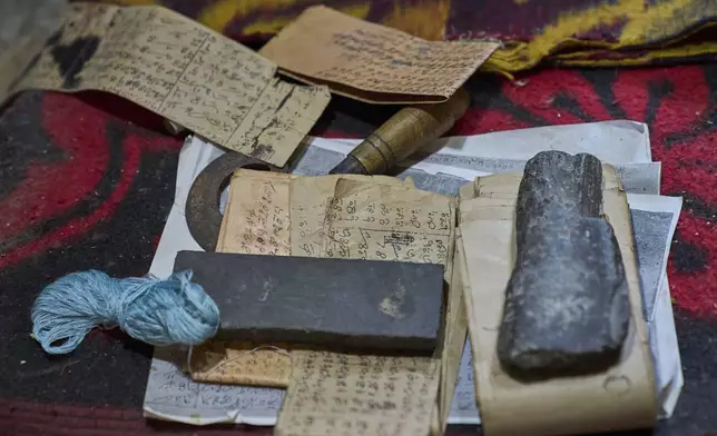 Knife-sharpening stones are used as paper weights for strips of paper with carpet weaving instructions at a factory in Srinagar, Indian controlled Kashmir, on April 14, 2025. (AP Photo/Dar Yasin)