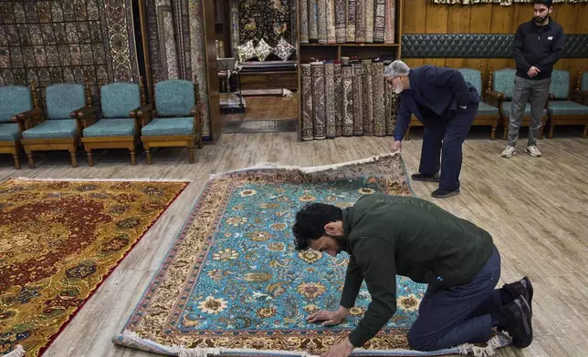Mohammad Iqbal Bakshi, left, and Mohammad Rafiq Shah inspect a Kashmiri hand-knotted silk carpet inside a showroom in Srinagar, Indian controlled Kashmir, on April 14, 2025. (AP Photo/Dar Yasin)