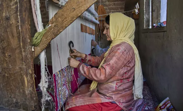 Shameema and her husband Mohammad Yousaf Dar weave a Kashmiri hand-knotted carpet at their home in Srinagar, Indian controlled Kashmir, on April 15, 2025. (AP Photo/Dar Yasin)