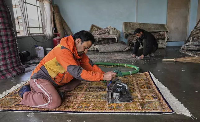 Ishfaq Ahmad Mir, left, and Altaf Ahmed shear Kashmiri hand-knotted carpets to remove protruding fibres at a workshop in Srinagar, Indian controlled Kashmir, on April 12, 2025. (AP Photo/Dar Yasin)