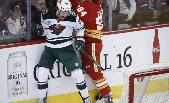 Minnesota Wild's Frederick Gaudreau (89) checks Calgary Flames' Brayden Pachal (94) during the second period of an NHL hockey game in Calgary, Alberta, Friday, April 11, 2025. (Jeff McIntosh/The Canadian Press via AP)