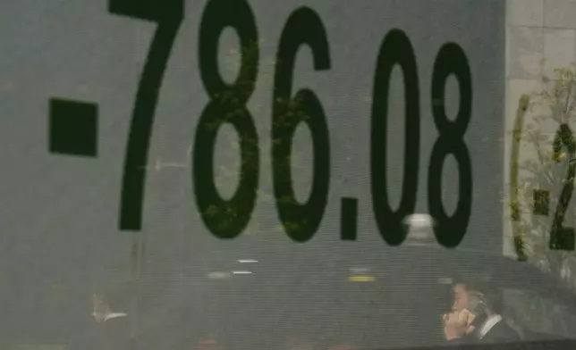 A man talking on the phone is reflected on a screen showing Japan's Nikkei 225 index at a securities firm in Tokyo, Wednesday, April 9, 2025. (AP Photo/Hiro Komae)