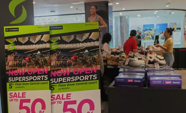 Shoppers are seen behind a sales advertisement at a shopping mall in Bangkok, Thailand, Wednesday, April 9, 2025. (AP Photo/Sakchai Lalit)