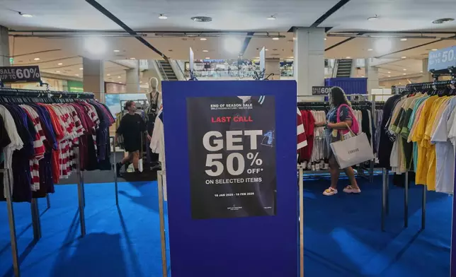 Shopper are seen behind a sales advertisement at a shopping mall in Bangkok, Thailand, Wednesday, April 9, 2025. (AP Photo/Sakchai Lalit)