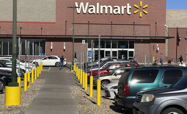 FILE - Shoppers head into and out of a Walmart store, Feb. 7, 2025, in Englewood, Colo. (AP Photo/David Zalubowski, File)