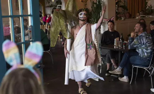 Drag performer Ed Du'Bull walks with a cross made to look like lit joints as he performs during a "blaze and praise" drag brunch at Bar Carlo on Sunday, April 20, 2025, in Portland, Ore. (AP Photo/Jenny Kane)